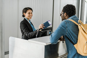 Africa Unted Airlines. smiling african american airport worker giving passport and air ticket to tourist with backpack